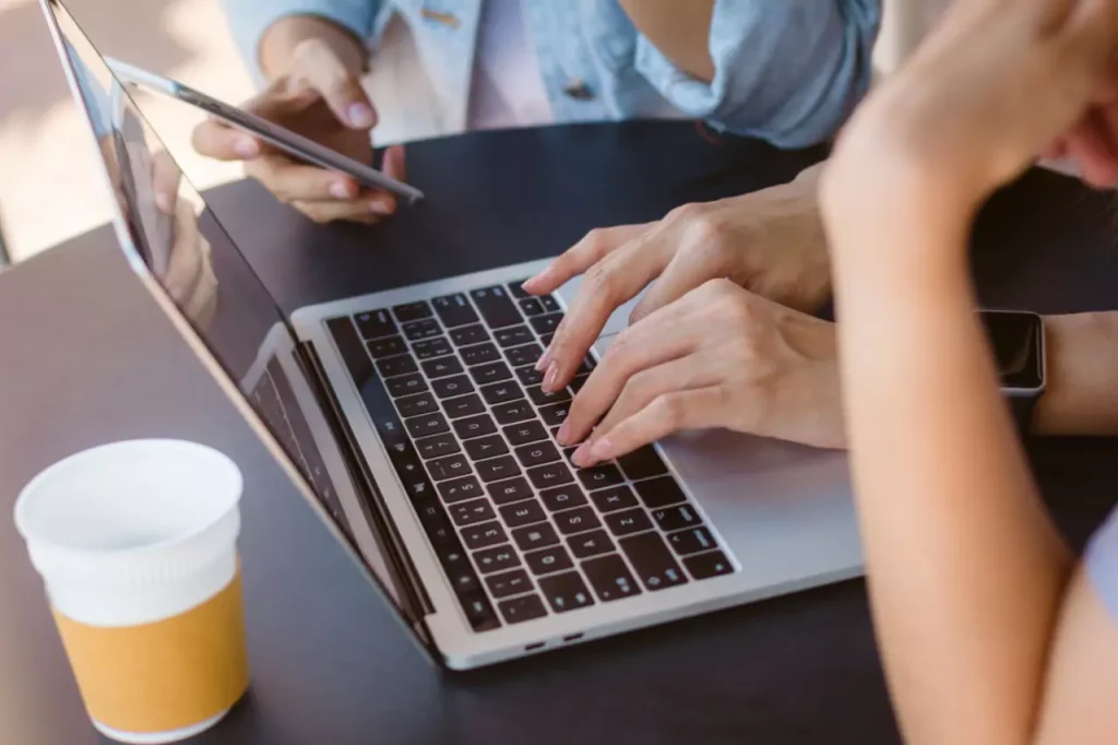 working laptop using looking smartphone drinking coffee